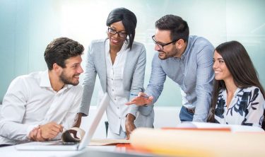 Three people are laughing together at a meeting.